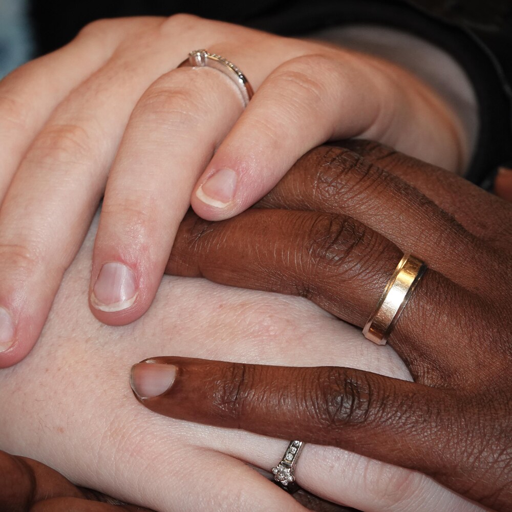 Les mains d'un homme et d'une femme portant chacun une alliance.