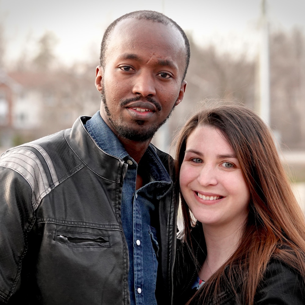 Un homme et une femme souriant à la caméra.