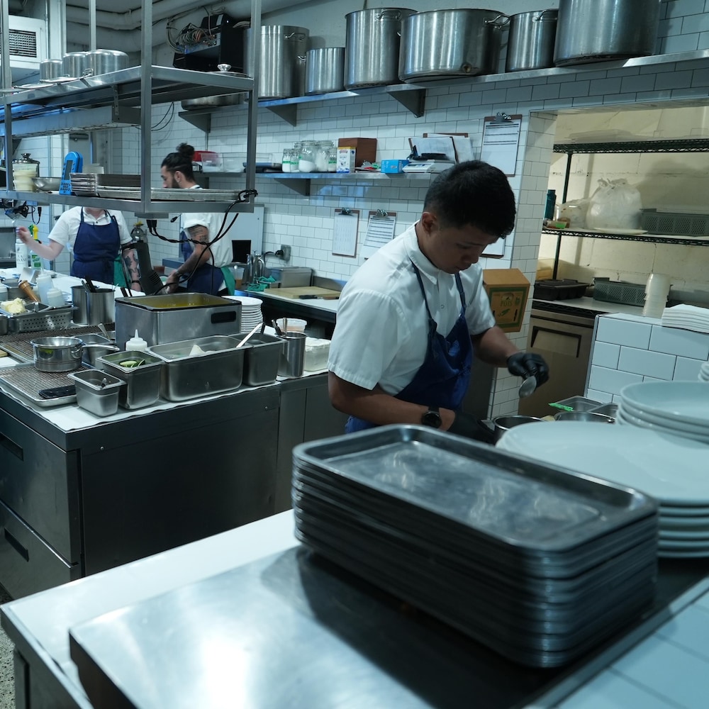 Des travailleurs en uniforme dans la cuisine d'un restaurant.