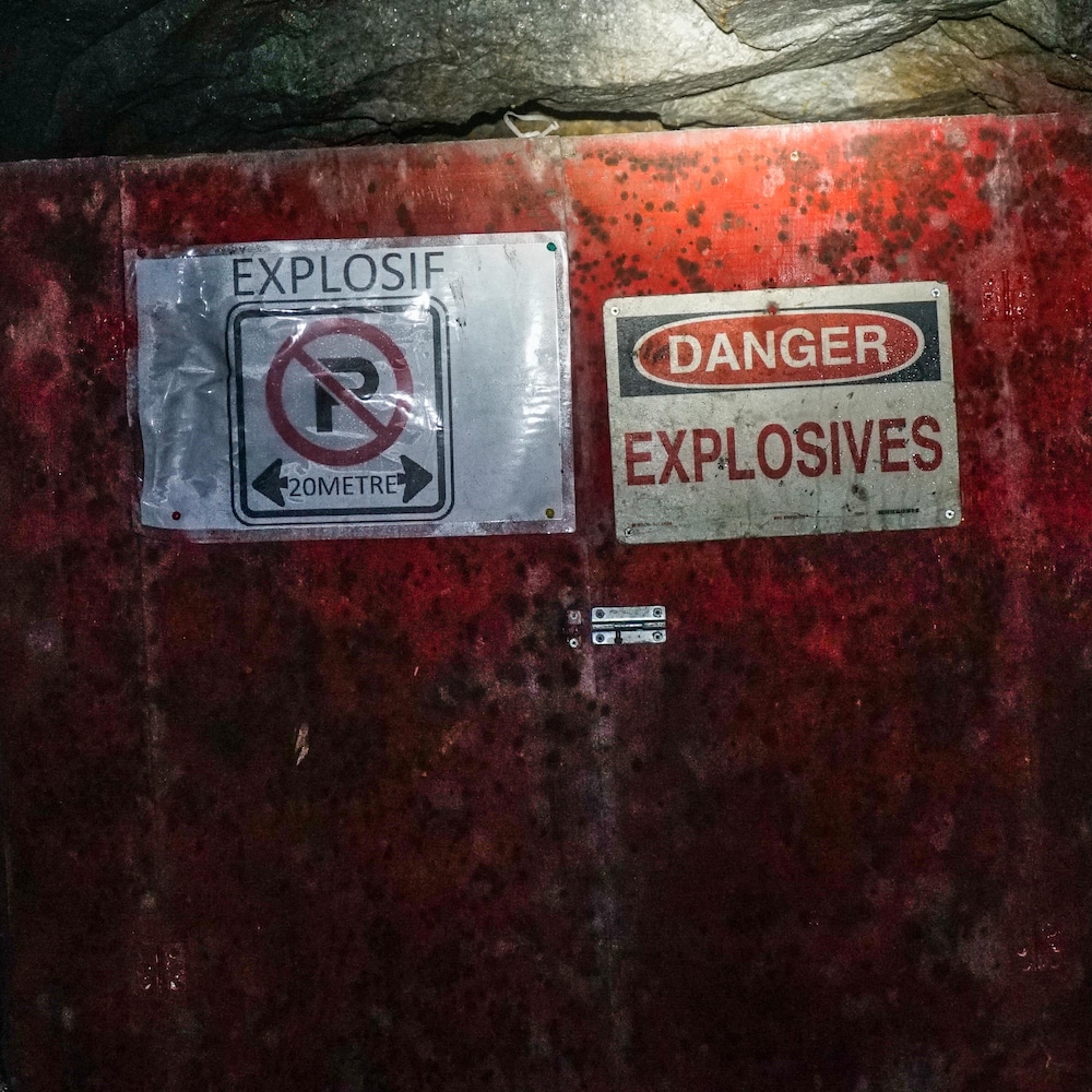 Une boite rouge installée au mur a deux affiches sur lesquelles on peut lire des avertissements en raison de la présence d'explosifs.