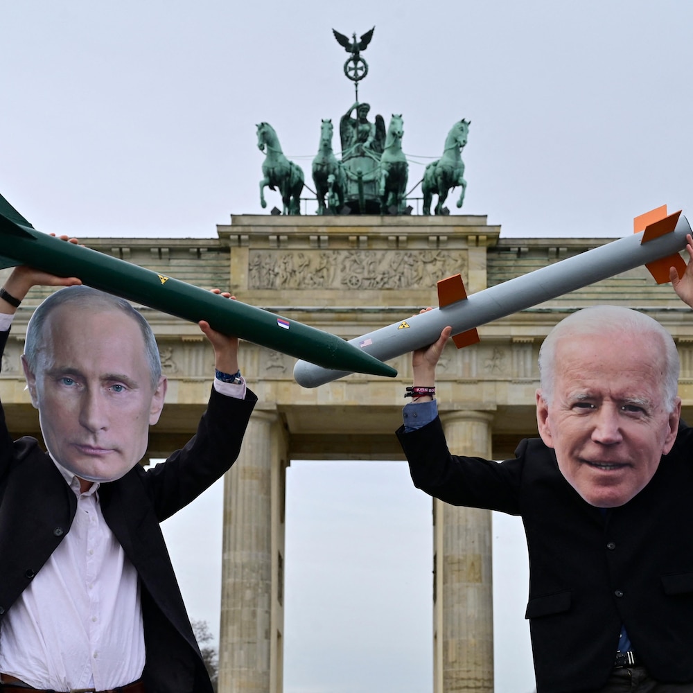 Deux activistes portant des masques de Vladimir Poutine et de Joe Biden tiennent de faux missiles nucléaires au-dessus de leur tête devant la porte de Brandebourg.