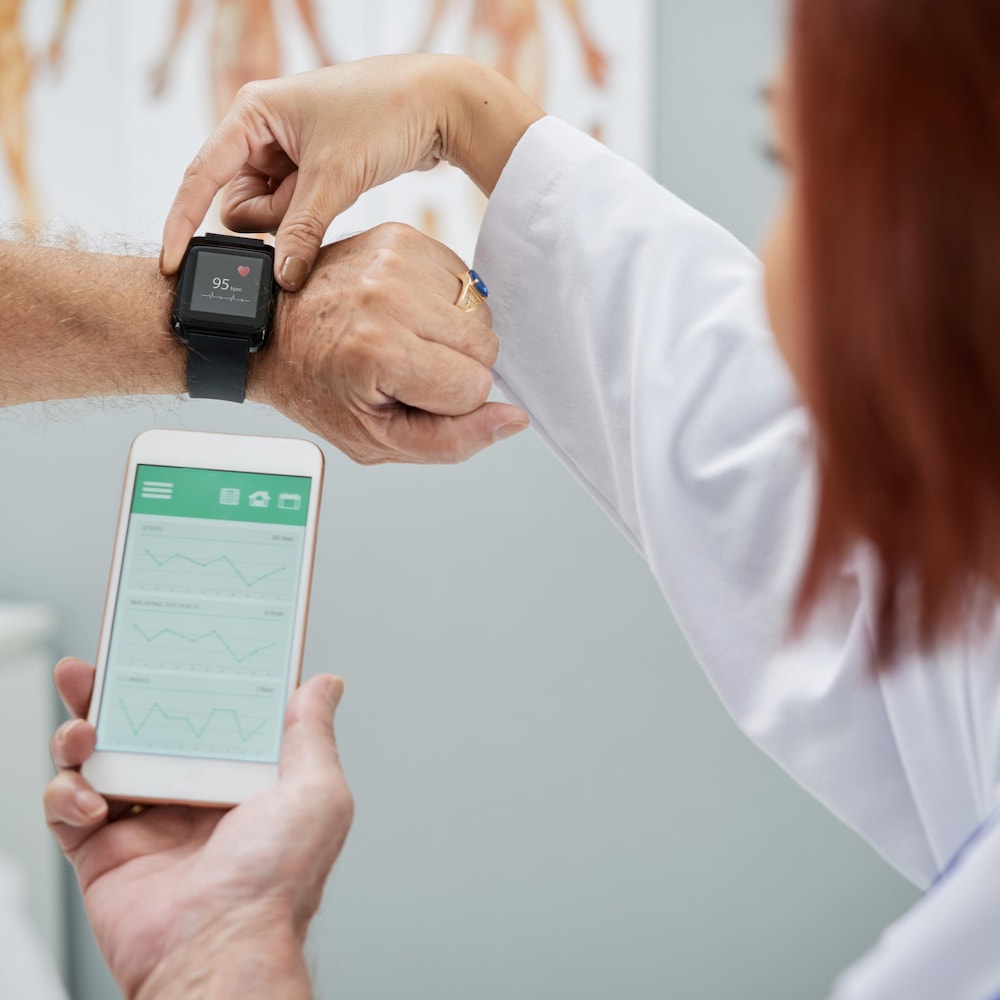 Une médecin explique à un patient âgé comment utiliser une application sur son téléphone intelligent.