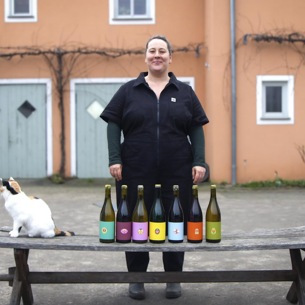La Québécoise Emily Campeau pose devant des bouteilles de vin de son vignoble Wein Goutte, en Allemagne.