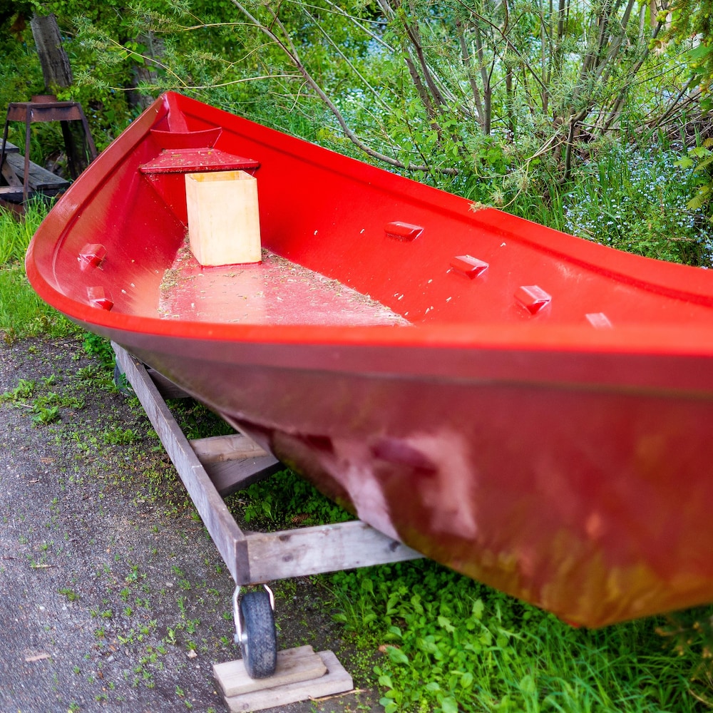 Une chaloupe rouge installée sur une base en bois à l'extérieur. 