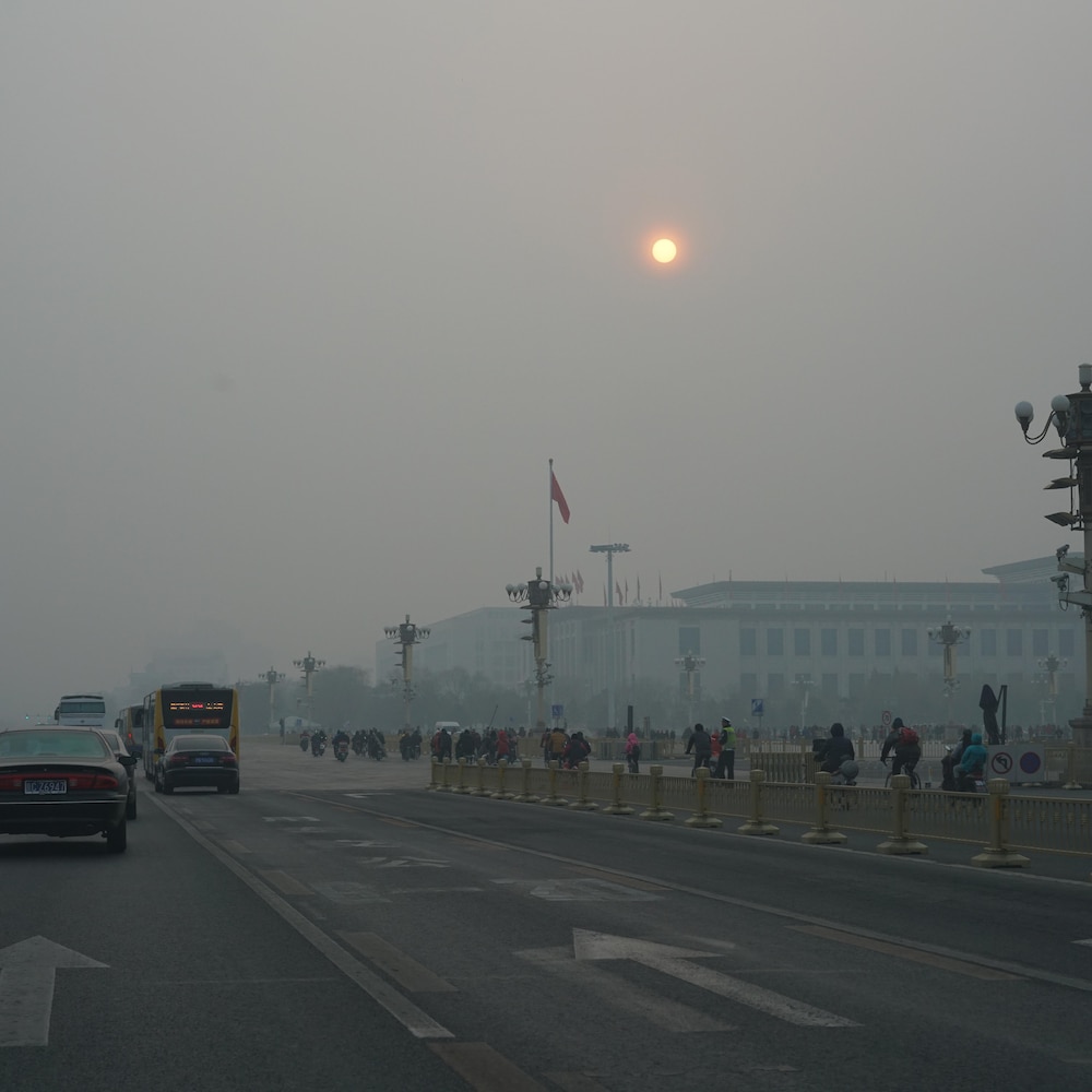 Une rue de Pékin sous le smog et un soleil obscurci.