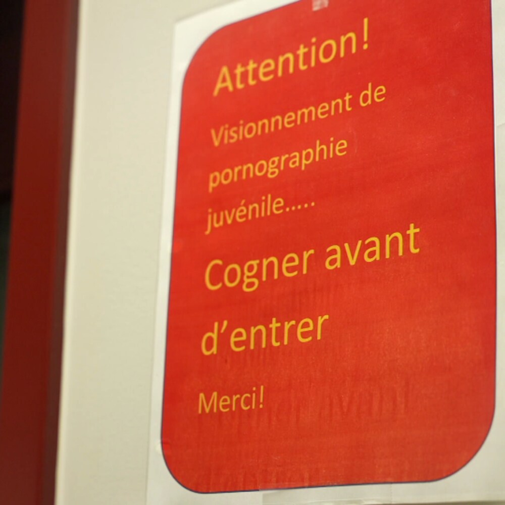 Une affiche avertissant qu'un visionnement de pornographie juvénile est en cours et demandant de cogner avant d'entrer