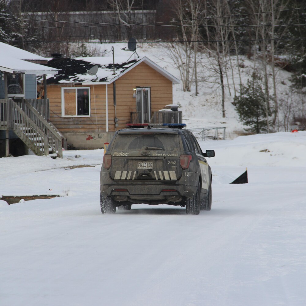 Une voiture de la SQ roule sur un chemin de neige. 