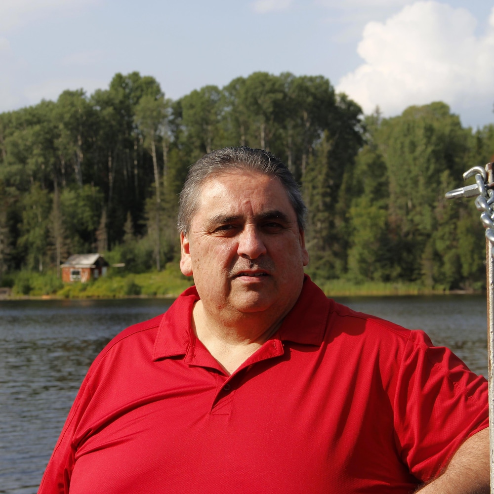 Un homme en chandail rouge au bord de la rivière des Outaouais.