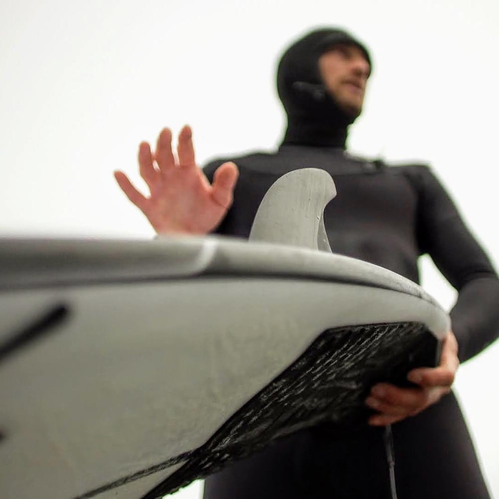 Peter DeVries en combinaison tenant sa planche de surf.