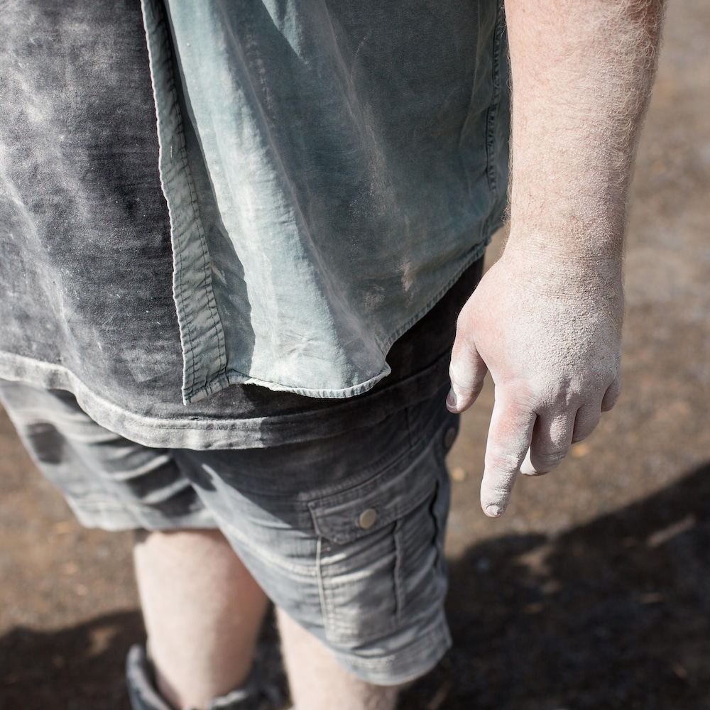 La main et les vêtements d'Adrien sont complètement recouverts d'une possière blanche.