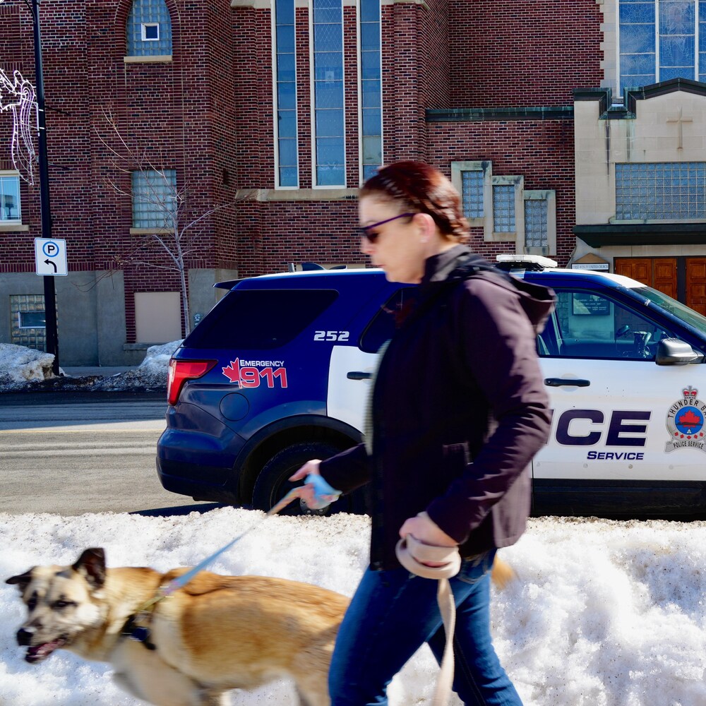 Une mère et sa fille passent devant une voiture de patrouille de la police de Thunder Bay.