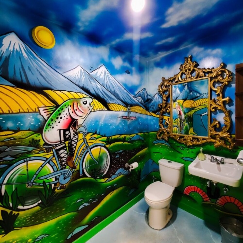 Les toilettes de Rollick Co., à Black Diamond, en Alberta avec des peintures au mur dont un poisson qui fait du vélo.