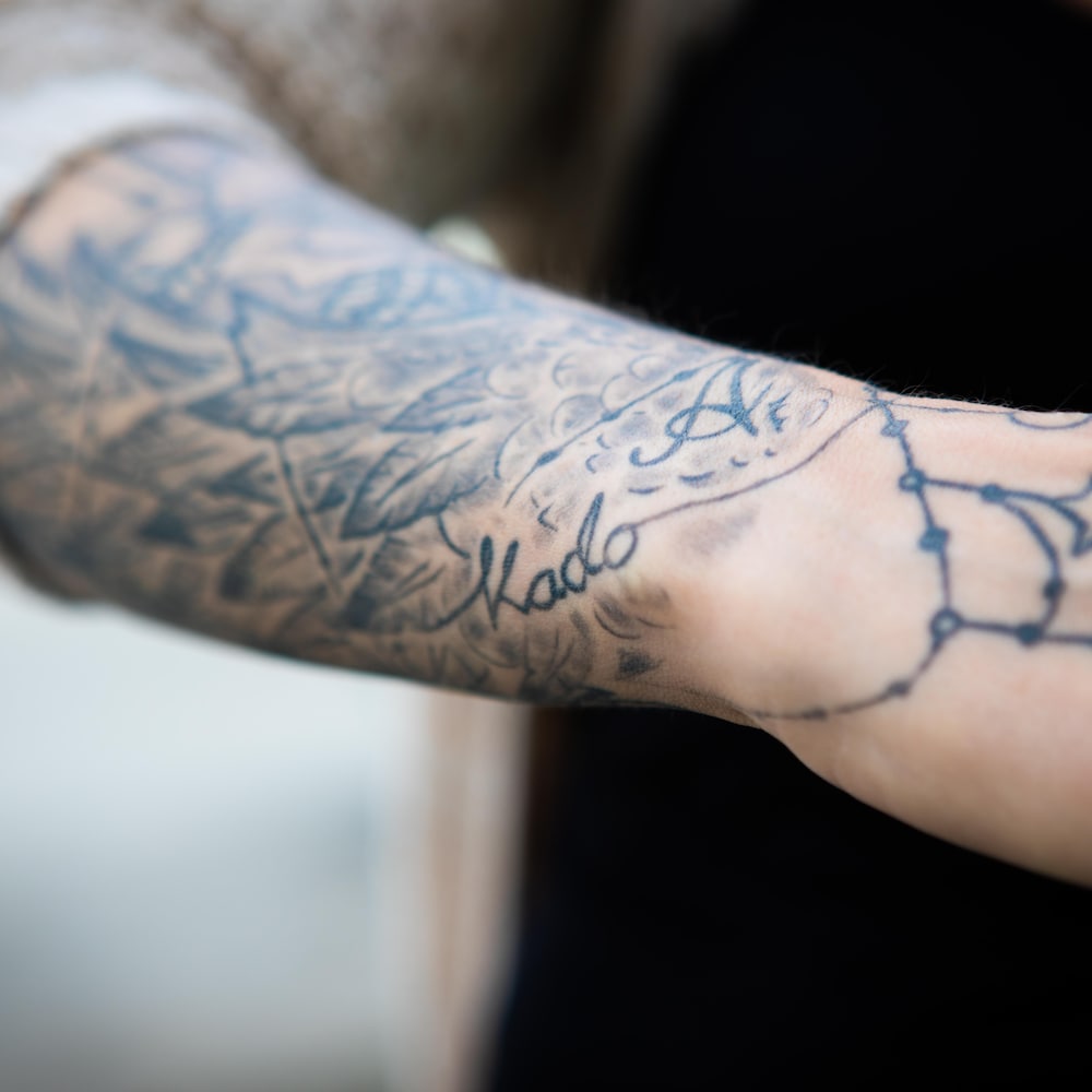 Un bras avec le tatouage de prénom Kado. 