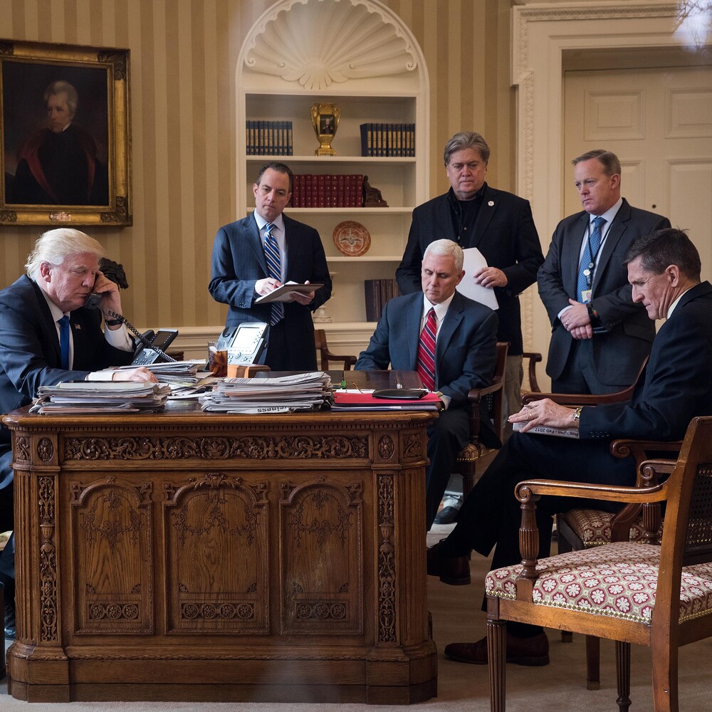 Donald Trump, assis à son bureau devant cinq collaborateurs.
