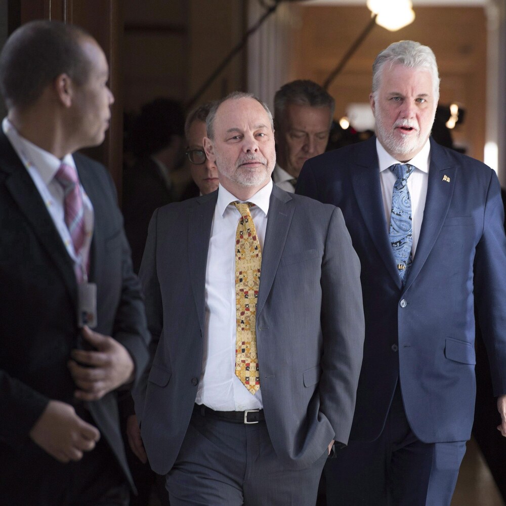 Philippe Couillard, Jean-Louis Dufresne et Harold Fortin marchent dans un corridor.