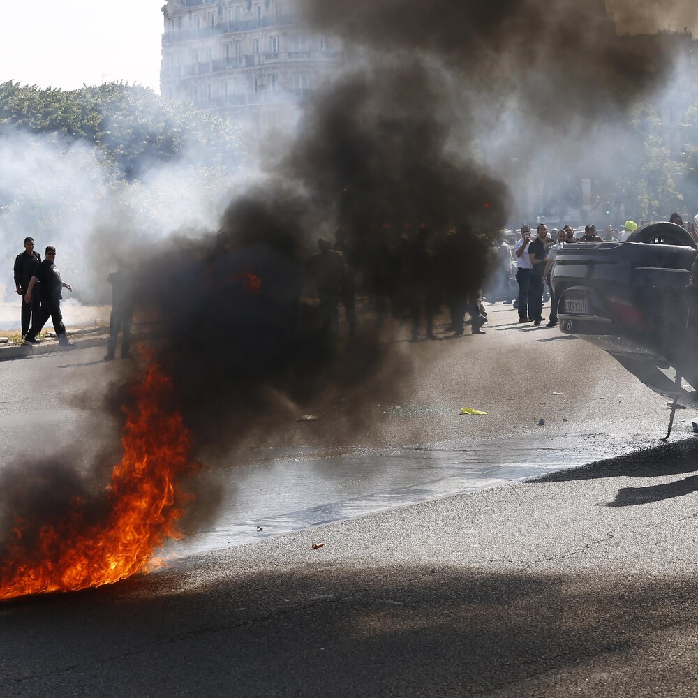Retournée sur le toit, une voiture brûle.