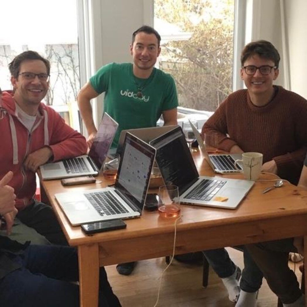 Les membres de l'équipe de VidDay assis autour d'une table travaillent chacun à son ordinateur. 