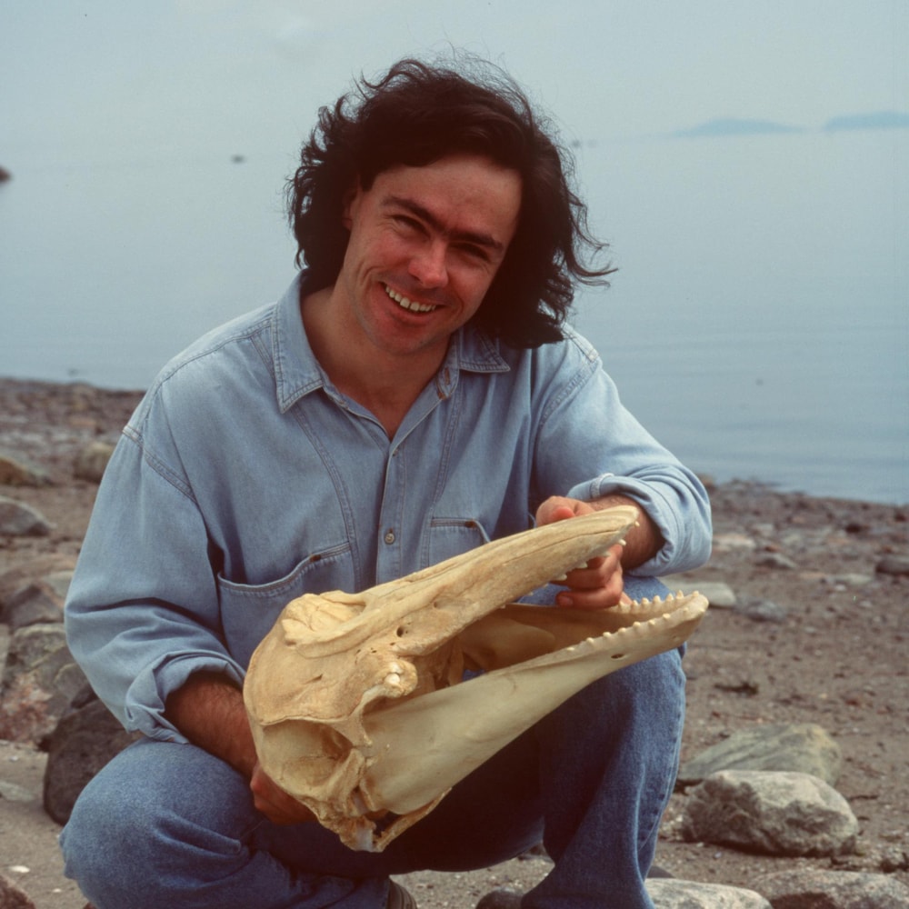 Le jeune Robert Michaud pose avec un crâne de béluga sur le rivage.