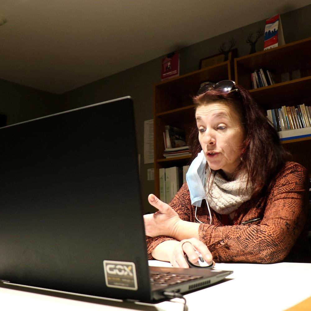 Une femme regarde son écran d'ordinateur, visiblement entrain de parler.