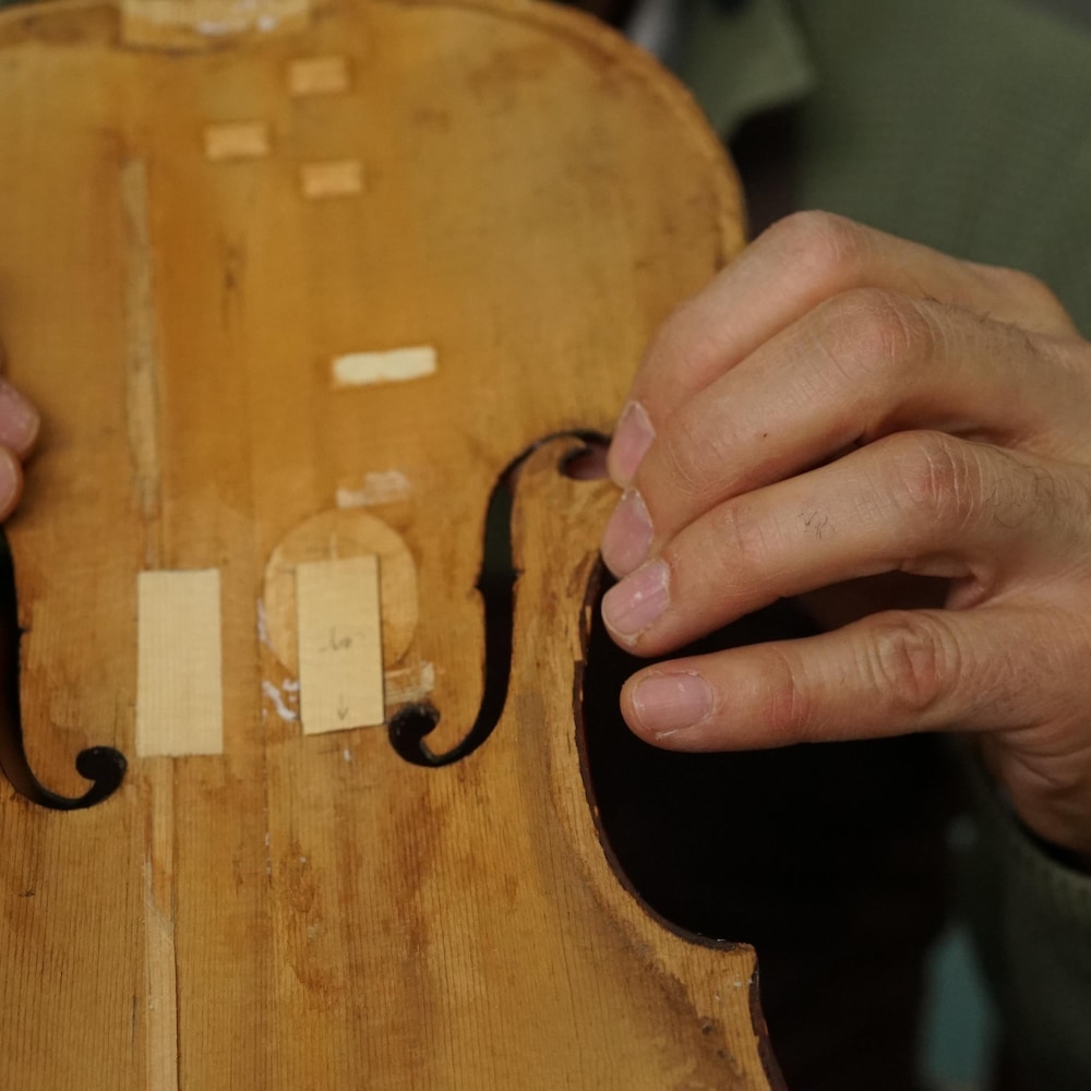 Les doigts du luthier ajustent la pièce dans la table d'harmonie d'un violon.