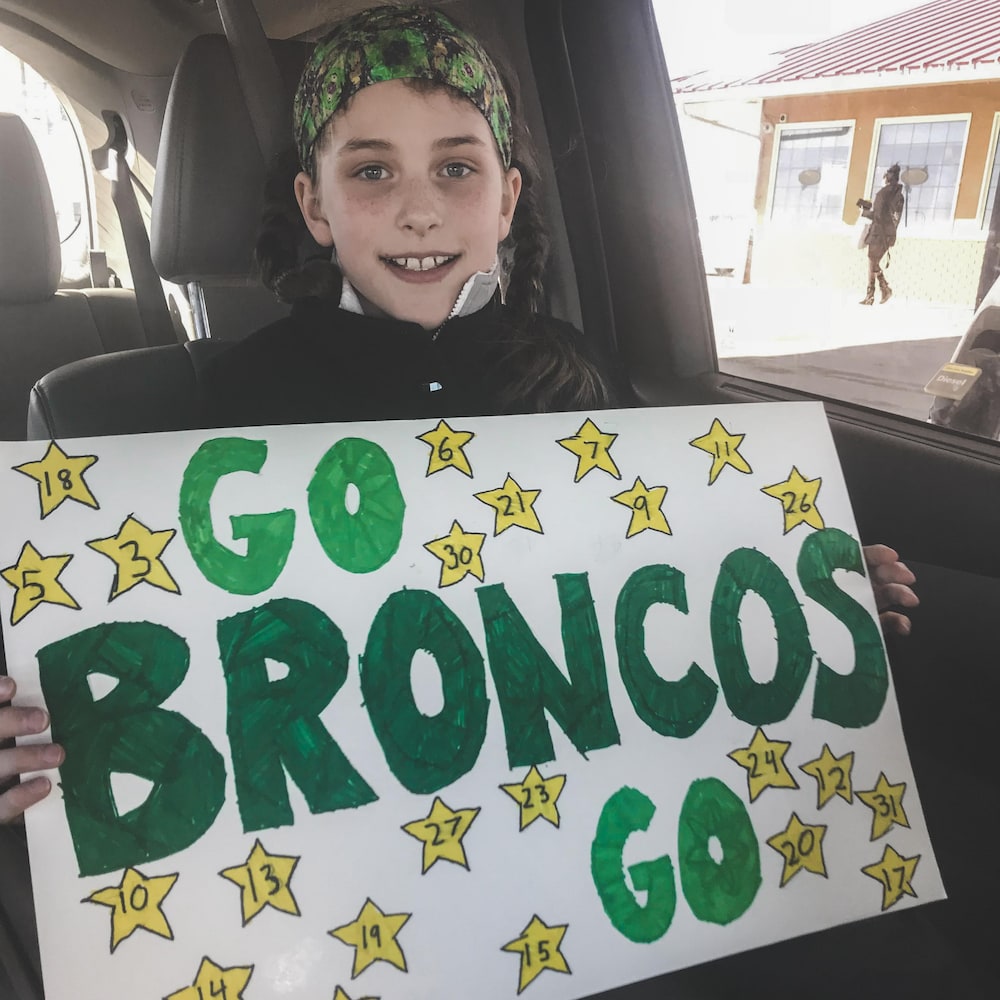 Jeune fille qui tient une pancarte en soutien aux Broncos de Humboldt