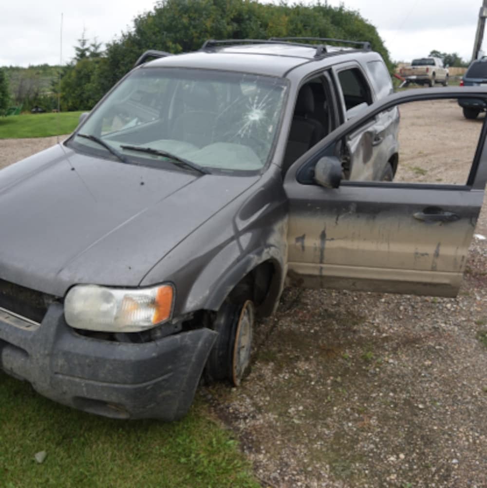 Un VUS gris accidenté avec un pneu crevé et le pare-brise craqué.