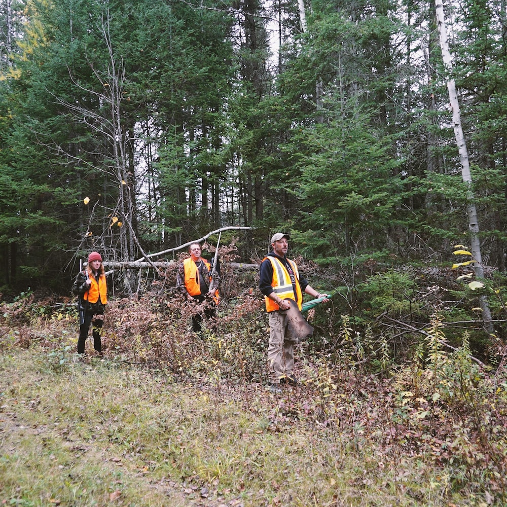 Trois chasseurs en forêt observent attentivement l'horizon.