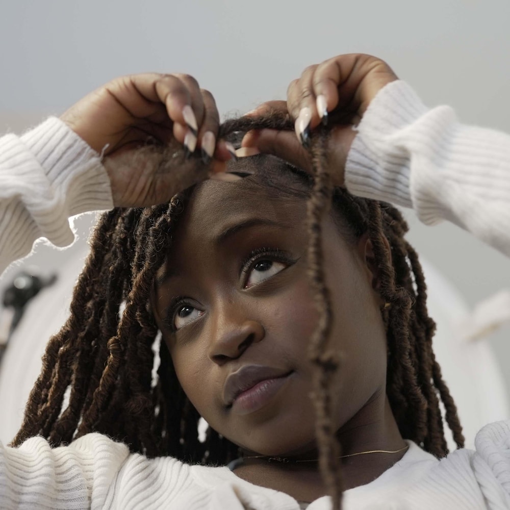 Une jeune femme noire qui se coiffe
