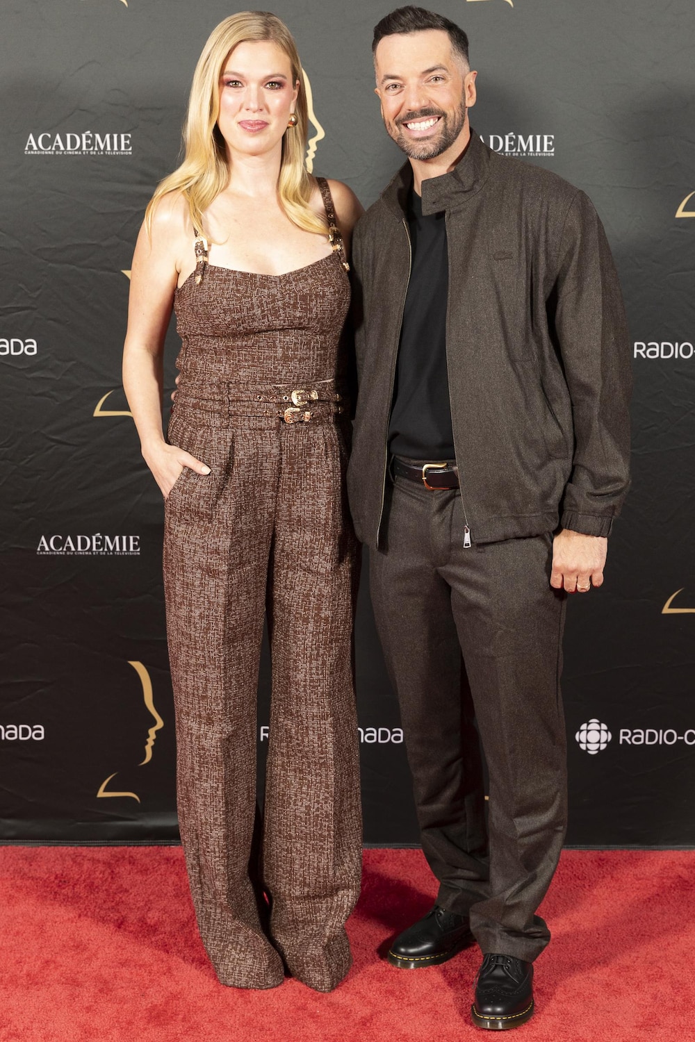 La femme et l'homme sourient sur le tapis rouge. 