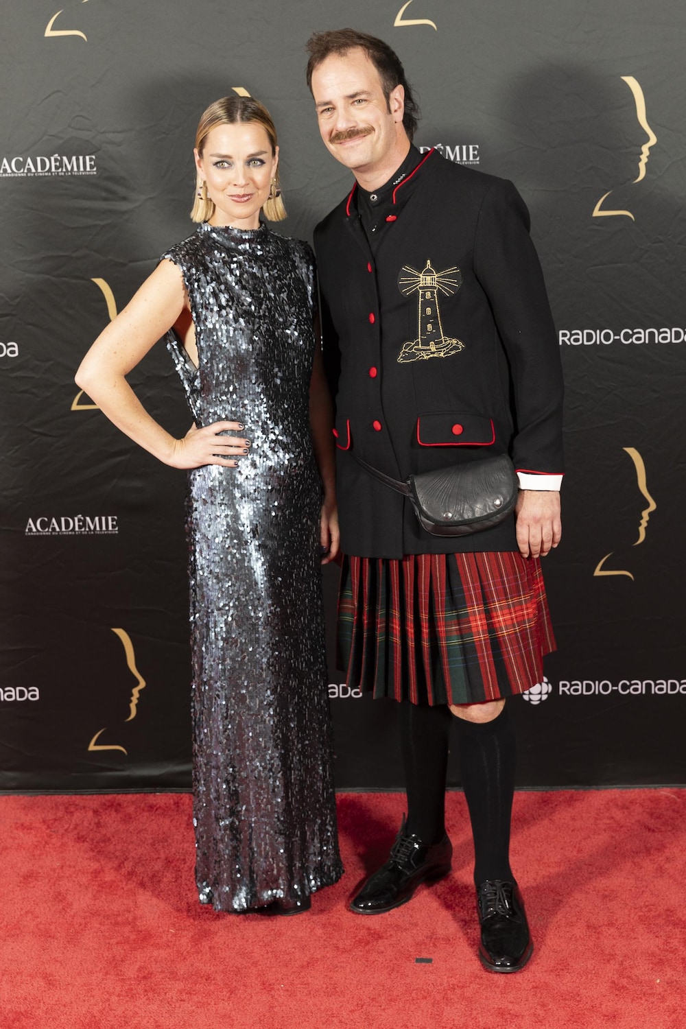 La femme et l'homme sourient sur le tapis rouge. 
