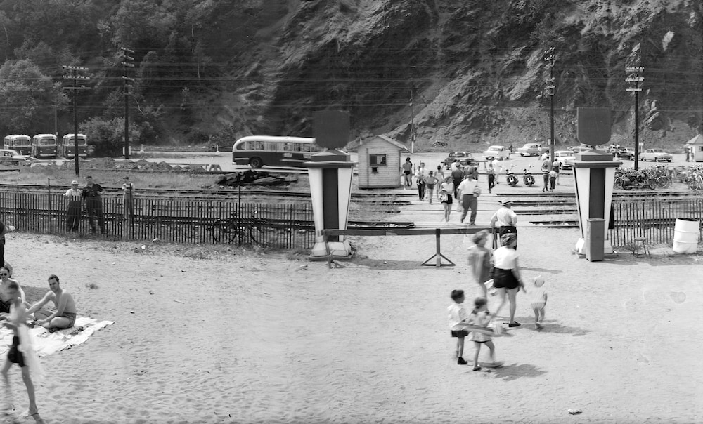 Des gens traversant les rails pour se rendre au stationnement de la plage dans les années 1950.                    