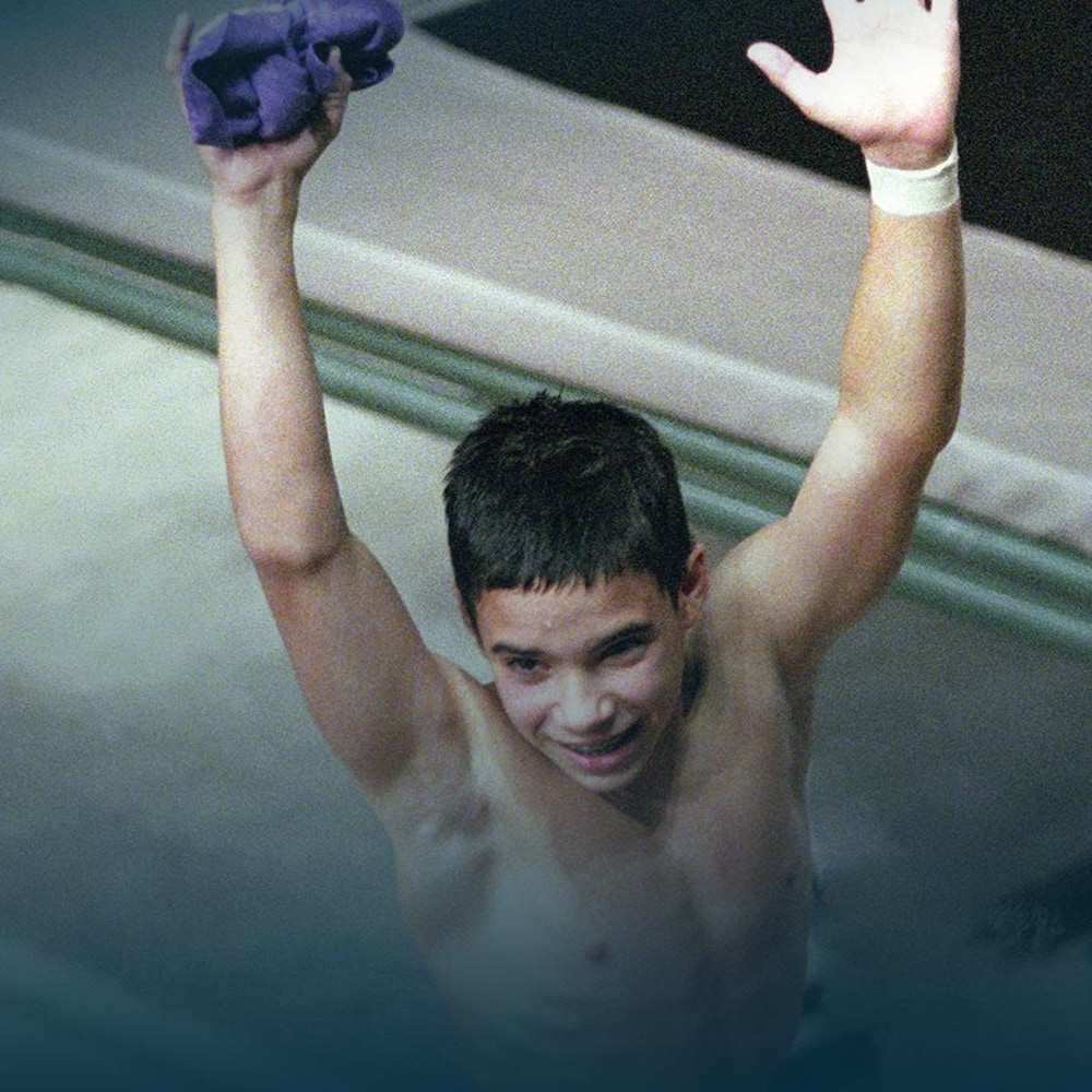Un jeune plongeur lève les bras en triomphe. 