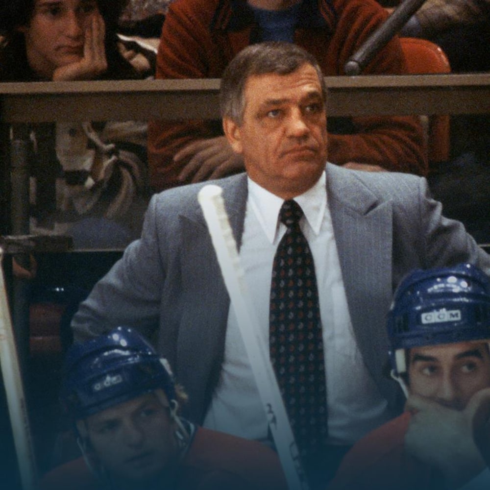 Posté derrière le banc du Canadien de Montréal, Bernard Geoffrion regarde l'action qui se déroule sur la patinoire.
