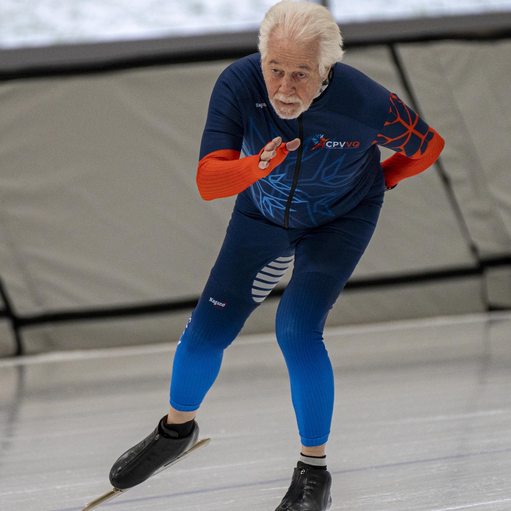 Un patineur de vitesse d'âge mûr patine sur un anneau de glace.