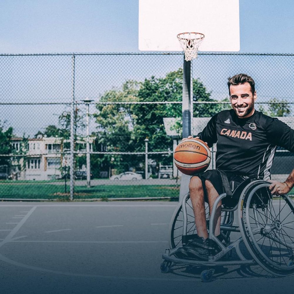 Jonathan Vermette tient un ballon de basketball et sourit.
