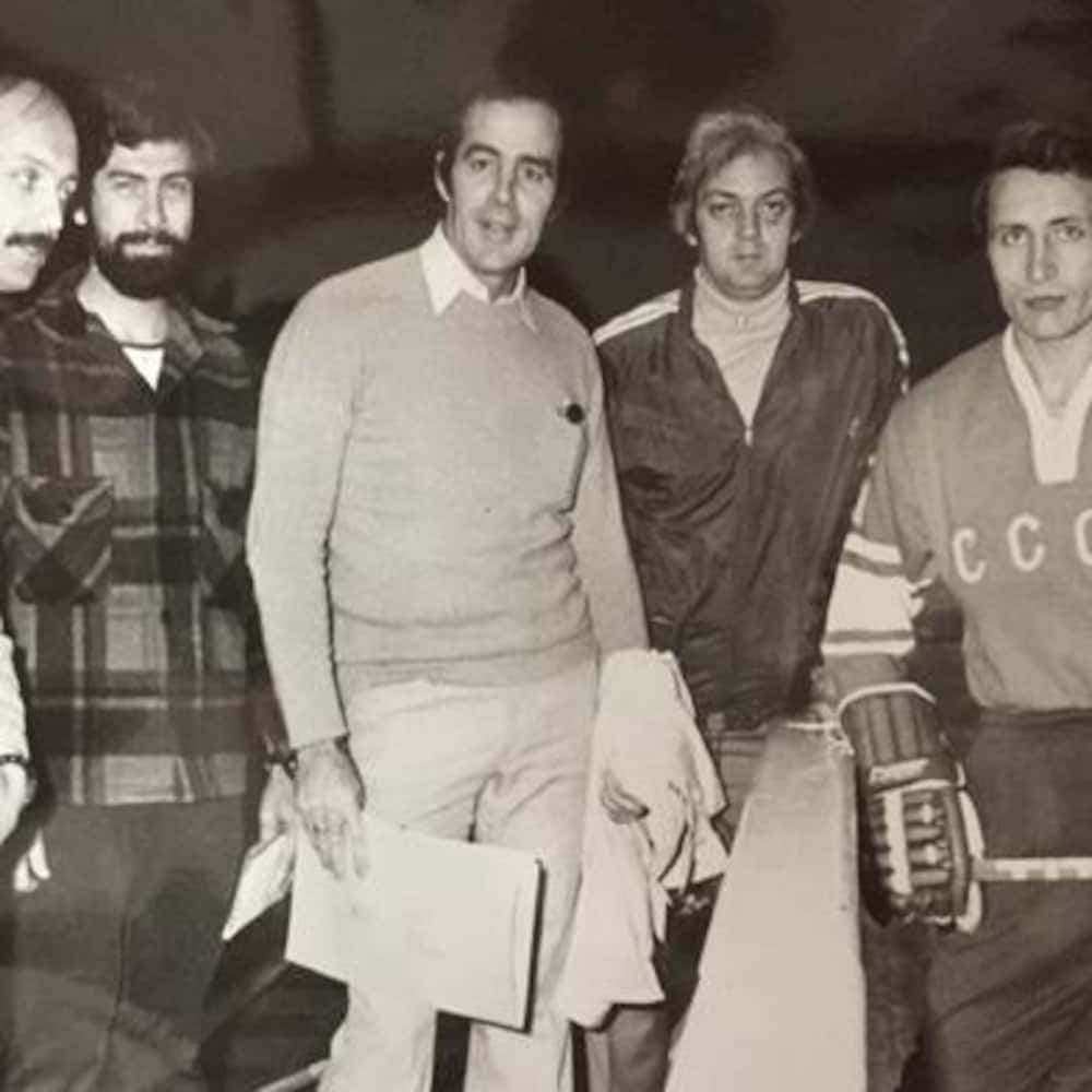 Cinq hommes près d'une glace où se trouve un hockeyeur