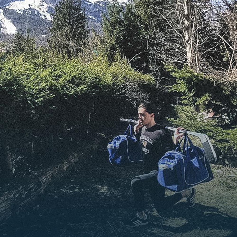 Mathieu Ayotte soulève deux sacs réunis par un bâton de hockey.
