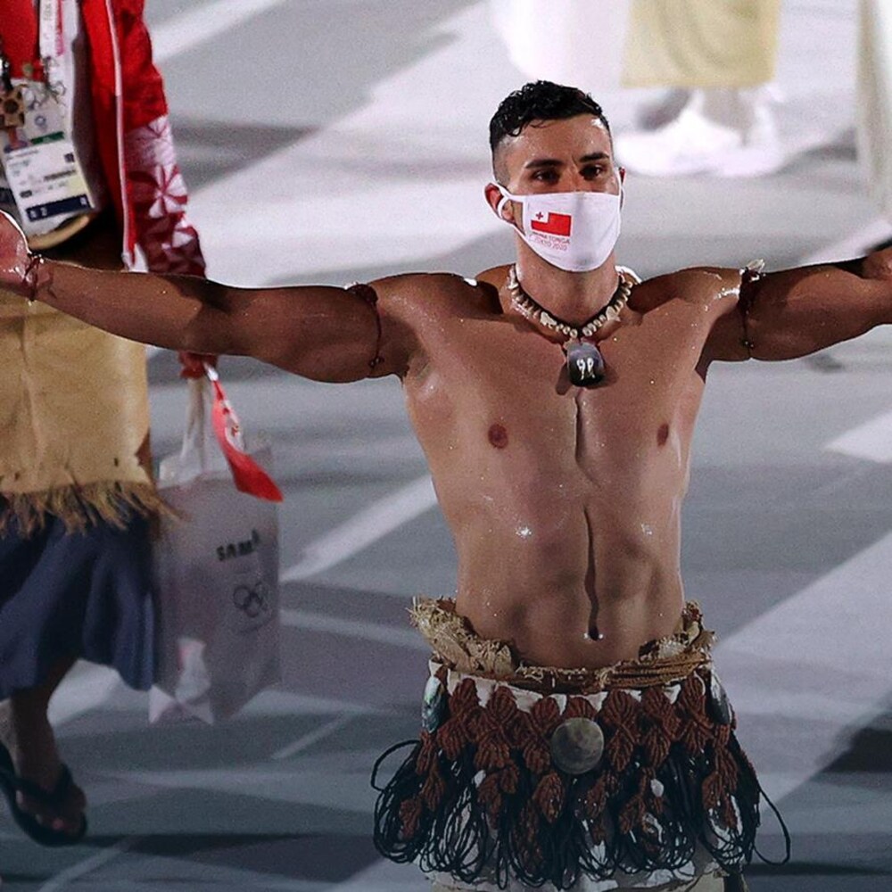 Un homme torse nu écarte les bras et regarde une foule.