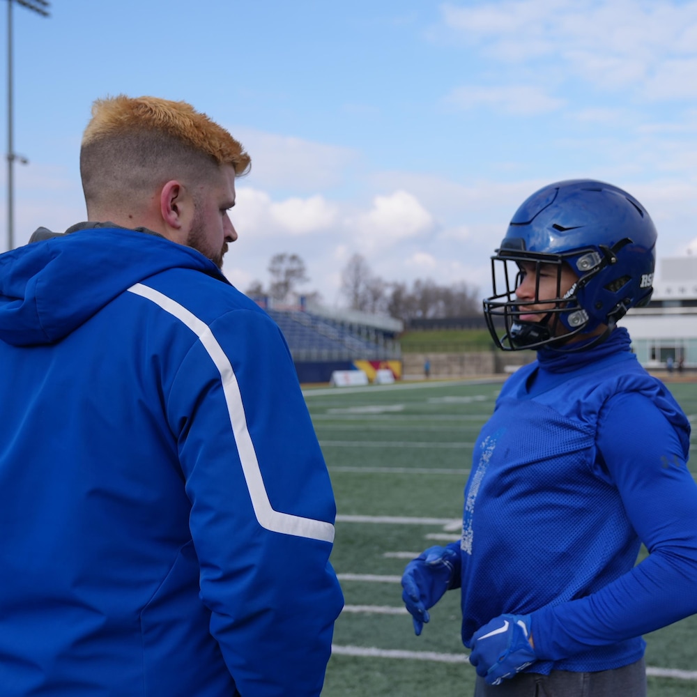 Un joueur de football discute avec un homme pendant un entraînement. 