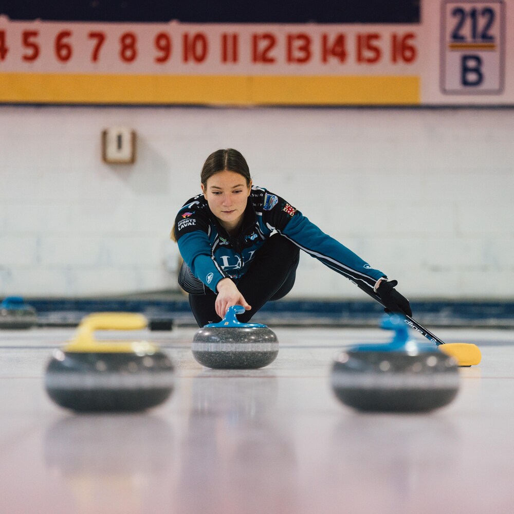 Une joueuse de curling lance une pierre.