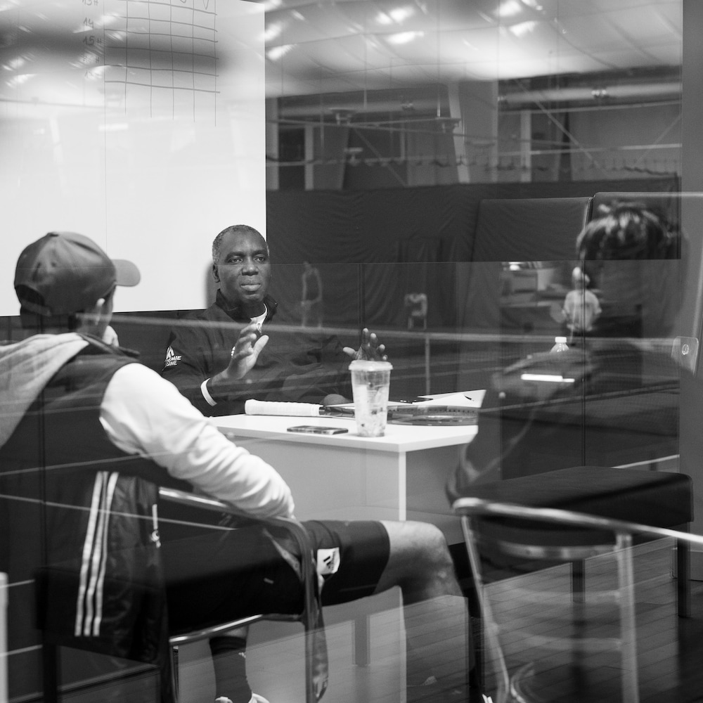 Photo en noir et blanc d'hommes qui discutent, assis à des bureaux