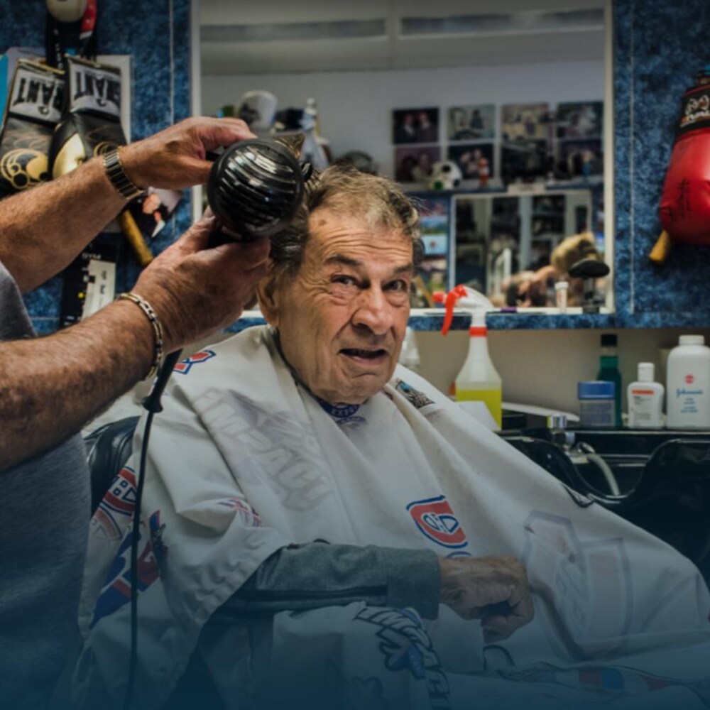 Assis sur une chaise de coiffeur, Régis Lévesque se fait sécher les cheveux.