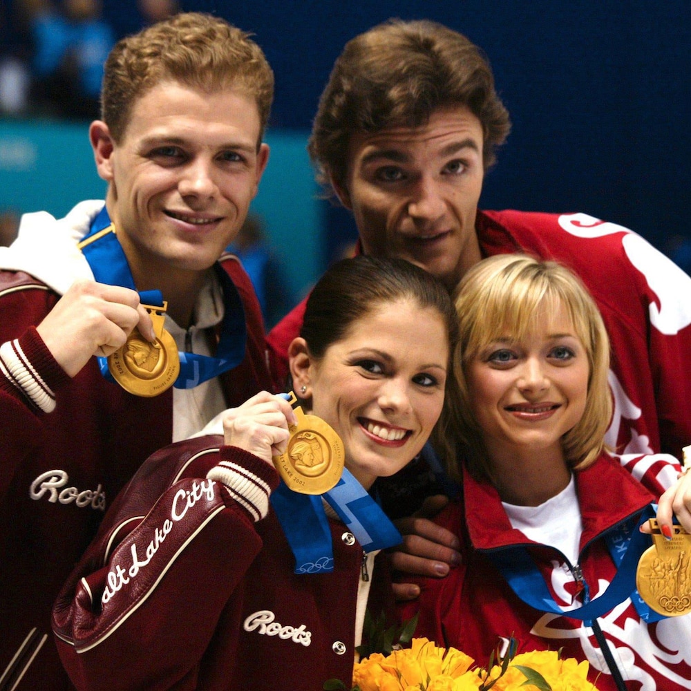 Quatre patineurs montrent fièrement leur médaille d'or. 