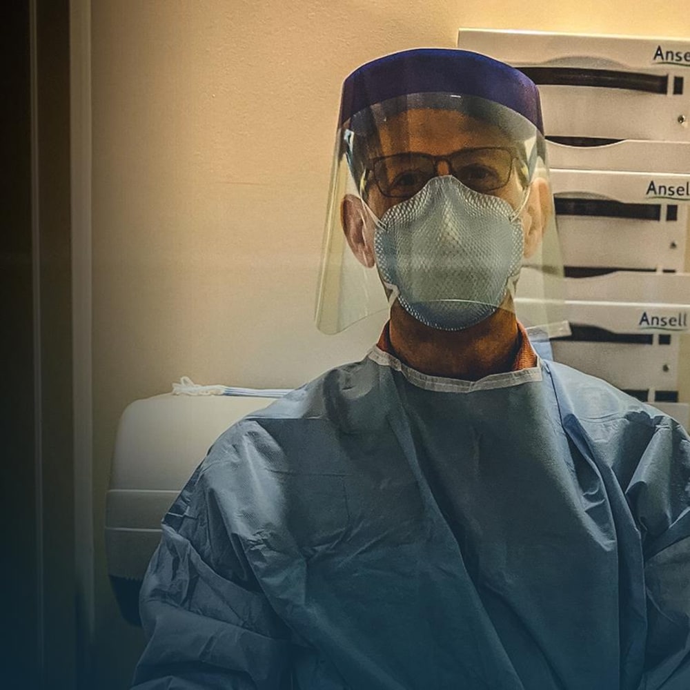 Sébastien Roulier, portant une visière et un masque médicaux, regarde la caméra.