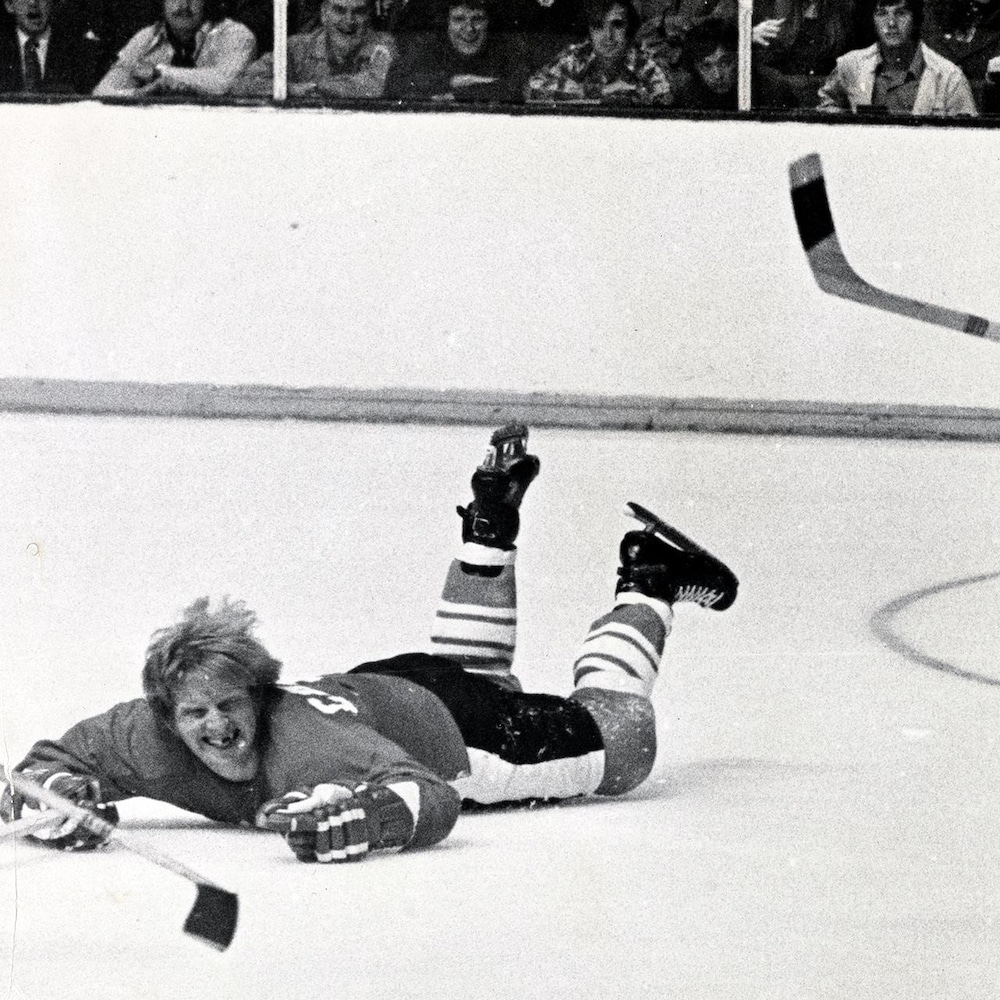 Un joueur étendu sur la glace regarde un adversaire prendre possession de la rondelle