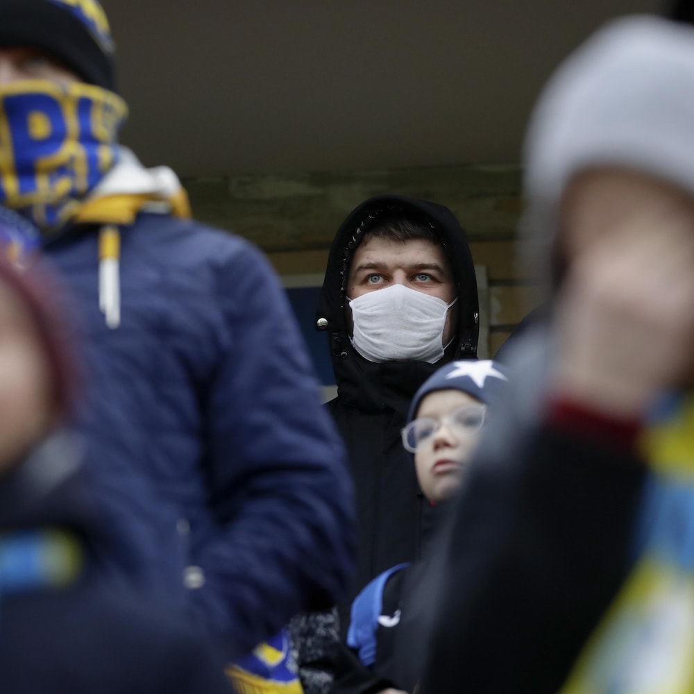 Des supporteurs du FC Bate, dont un qui porte un masque protecteur, assistent à une rencontre.