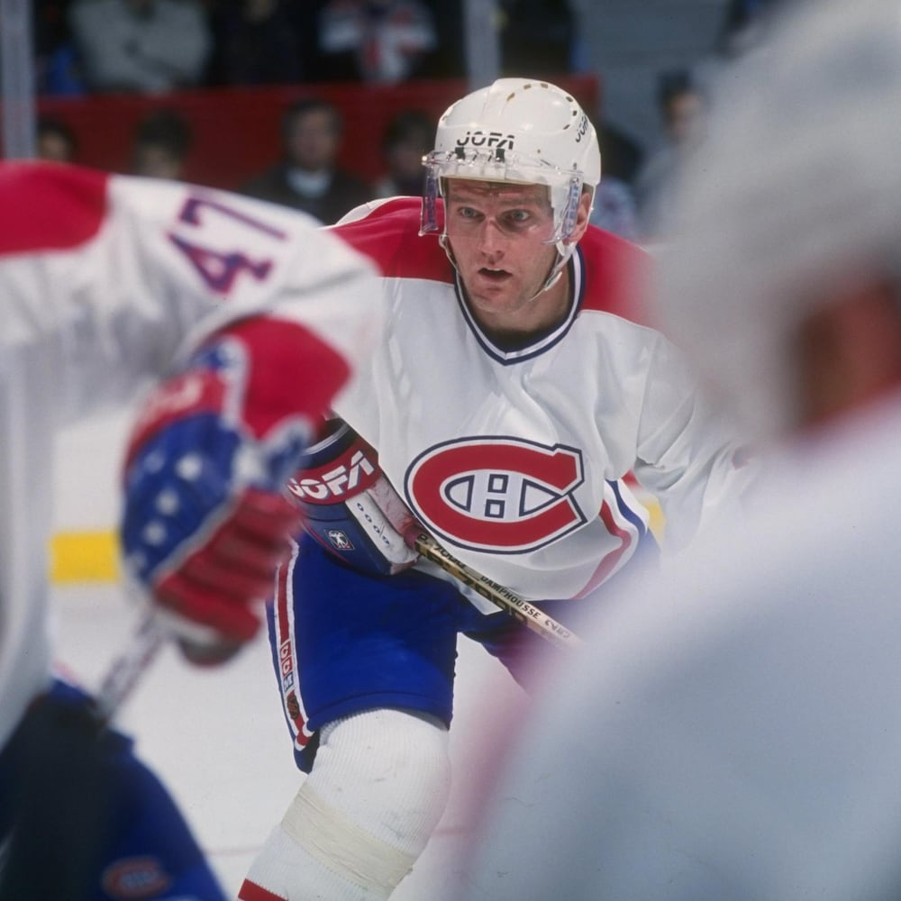 Un joueur de hockey regarde avec intensité l'action qui se déroule devant lui pendant un match.