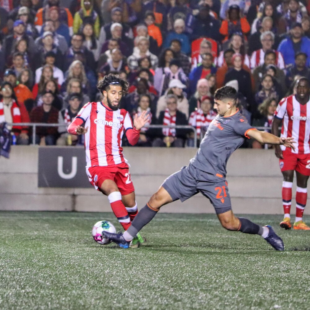 Un joueur de soccer tente de déjouer un adversaire, sans succès, pendant un match.