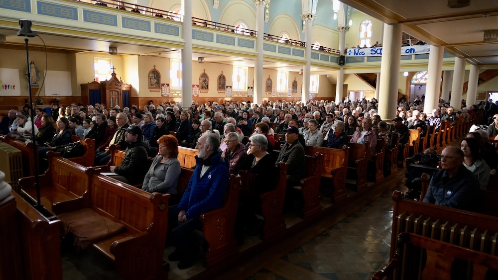 Des centaines de personnes dans une église. 