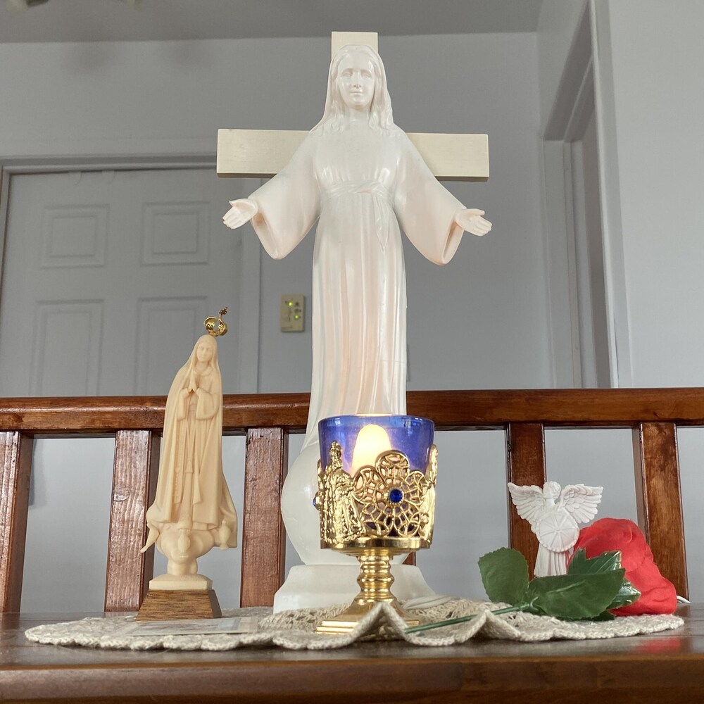 une table avec une bougie et deux statues de la vierge marie.
